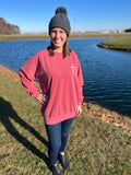 woman in crimson red crewneck with thin cross on left side chest