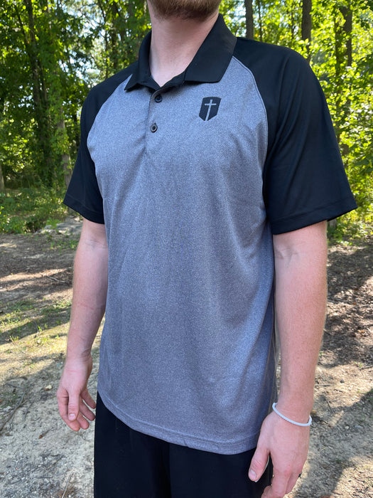 grey polo with black sleeves embroidered with a black cross in shield on front
