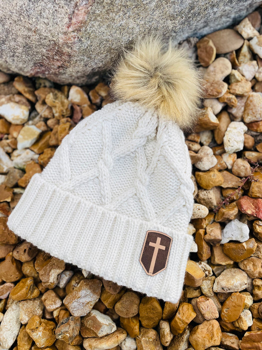 Cozy creamy white winter beanie with fur pom-pom and small leather cross patch